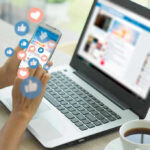 Person using smartphone and laptop with social media icons