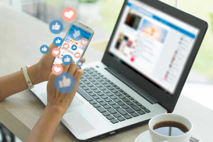Person using smartphone and laptop with social media icons