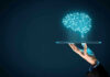 Digital brain above a hand holding a tablet
