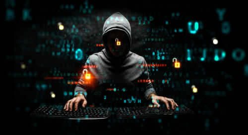Hooded hacker using two keyboards surrounded by code