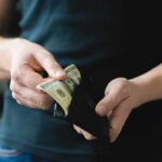 Person holding a wallet with cash inside
