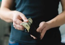 Person holding a wallet with cash inside