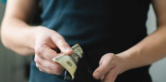 Person holding a wallet with cash inside
