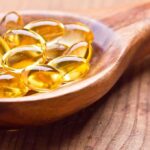 Golden omega 3 capsules in a wooden spoon