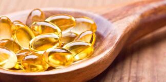 Golden omega 3 capsules in a wooden spoon