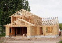 A partially constructed wooden house with exposed framing