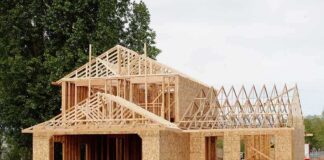 A partially constructed wooden house with exposed framing