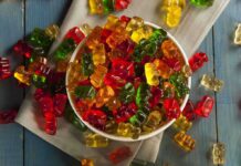 A bowl filled with colorful gummy bears surrounded by scattered candies