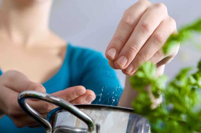 Person seasoning food with herbs from a pot