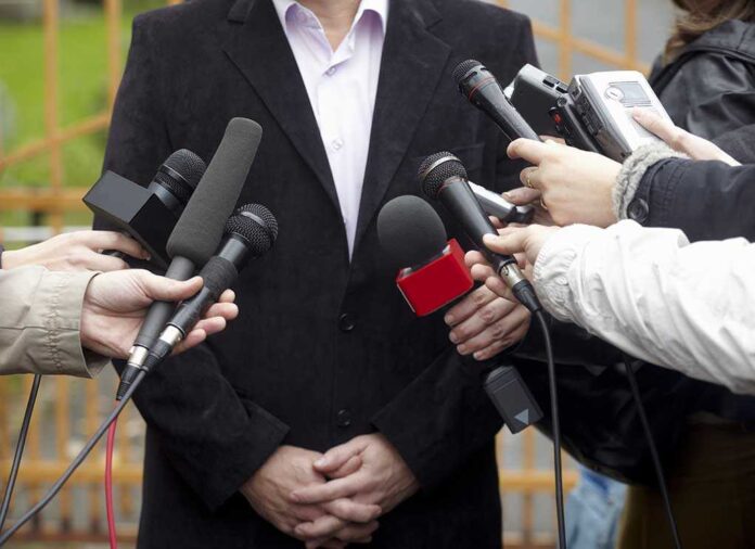 A group of microphones surrounding a person at a press conference