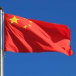 Chinese national flag waving against a clear blue sky