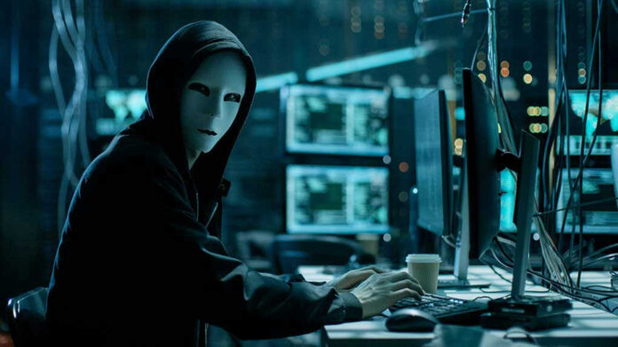 680078920 Person wearing mask and hoodie at computer desk