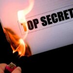 Why So SECRETIVE? — Navy Commandant’s ABRUPT Dismissal A hand holding a lighter igniting a paper labeled TOP SECRET as it catches fire