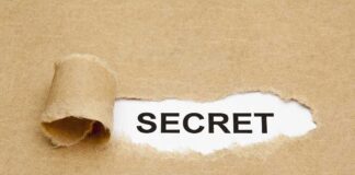 A torn piece of brown paper revealing the word SECRET underneath