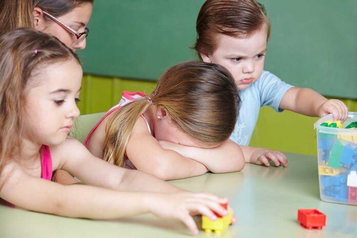 shutterstock_182289380.jpg Children at a table with building blocks, one child appears upset