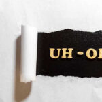 Jewel Thief Swallows Fortune – Now What? Torn paper revealing UH-OH text underneath.