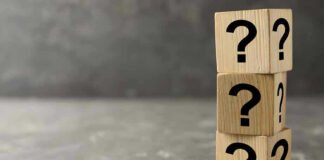 Three wooden blocks with black question marks stacked.