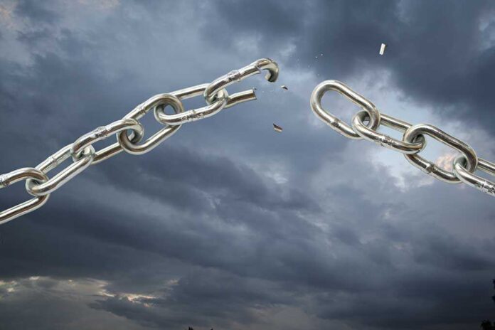 A broken metal chain against a stormy sky