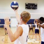 A young athlete preparing to serve a volleyball during practice