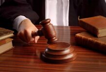 A judges hand holding a gavel over a wooden desk with law books