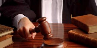 A judges hand holding a gavel over a wooden desk with law books