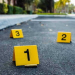 Justice System FAILED — Three Dead Next Day Crime scene markers on asphalt with bullet casing.