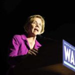 Warren Booby-Traps Pentagon Bill With Housing Bomb A female politician delivering a speech at a podium with a campaign sign