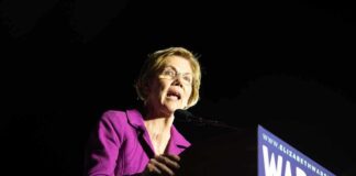 A female politician delivering a speech at a podium with a campaign sign