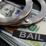 Handcuffs resting on a stack of cash with a 'BAIL' label