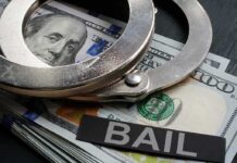 Handcuffs resting on a stack of cash with a 'BAIL' label