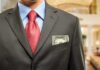 Man in a suit with a red tie and money peeking from his pocket