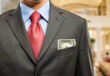 Man in a suit with a red tie and money peeking from his pocket