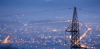 Night view of a city skyline with power lines in the foreground