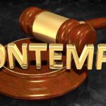 A wooden gavel resting on a circular base with the word CONTEMPT in gold letters