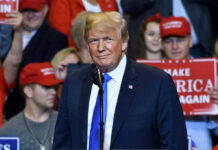 Person at a rally with Make America Great Again signs.