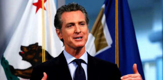 Man speaking with flags in the background