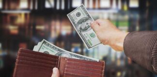 A hand withdrawing cash from a wallet in a blurred background