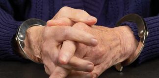 Close-up of hands in handcuffs resting on a table