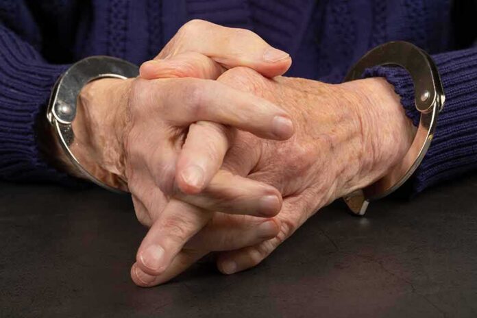 shutterstock_1651479037 (1).jpg Close-up of hands in handcuffs resting on a table