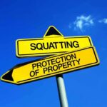 Two yellow signs indicating Squatting and Protection of Property against a blue sky