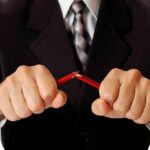Businessman in a suit breaking a pencil with his hands