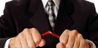 Businessman in a suit breaking a pencil with his hands