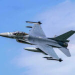 Jet fighter flying through clear blue sky.