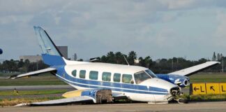 Damaged blue and white small airplane on an airport runway