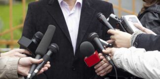 A group of microphones surrounding a person at a press conference