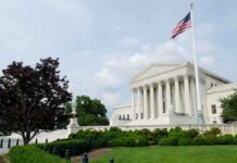 The U.S. Supreme Court building with an American flag and landscaped grounds