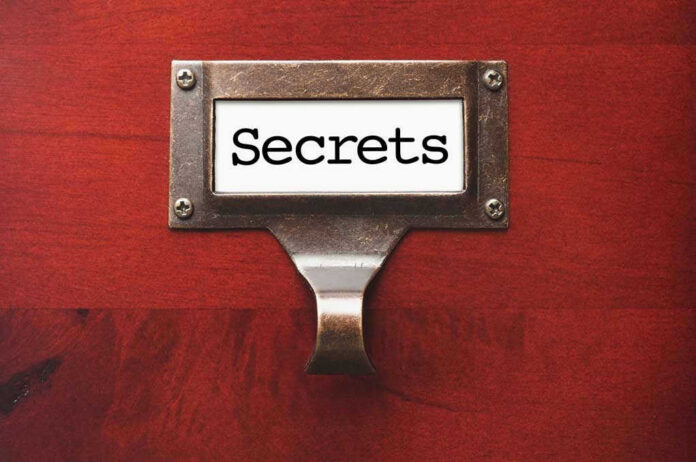 Metal label holder saying Secrets on wood background