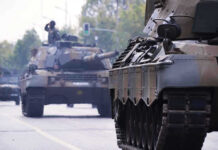 Tanks on a road with soldiers inside.