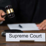 Judge with gavel and Supreme Court nameplate.