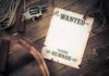 A vintage wanted poster alongside a revolver and rope on a wooden table